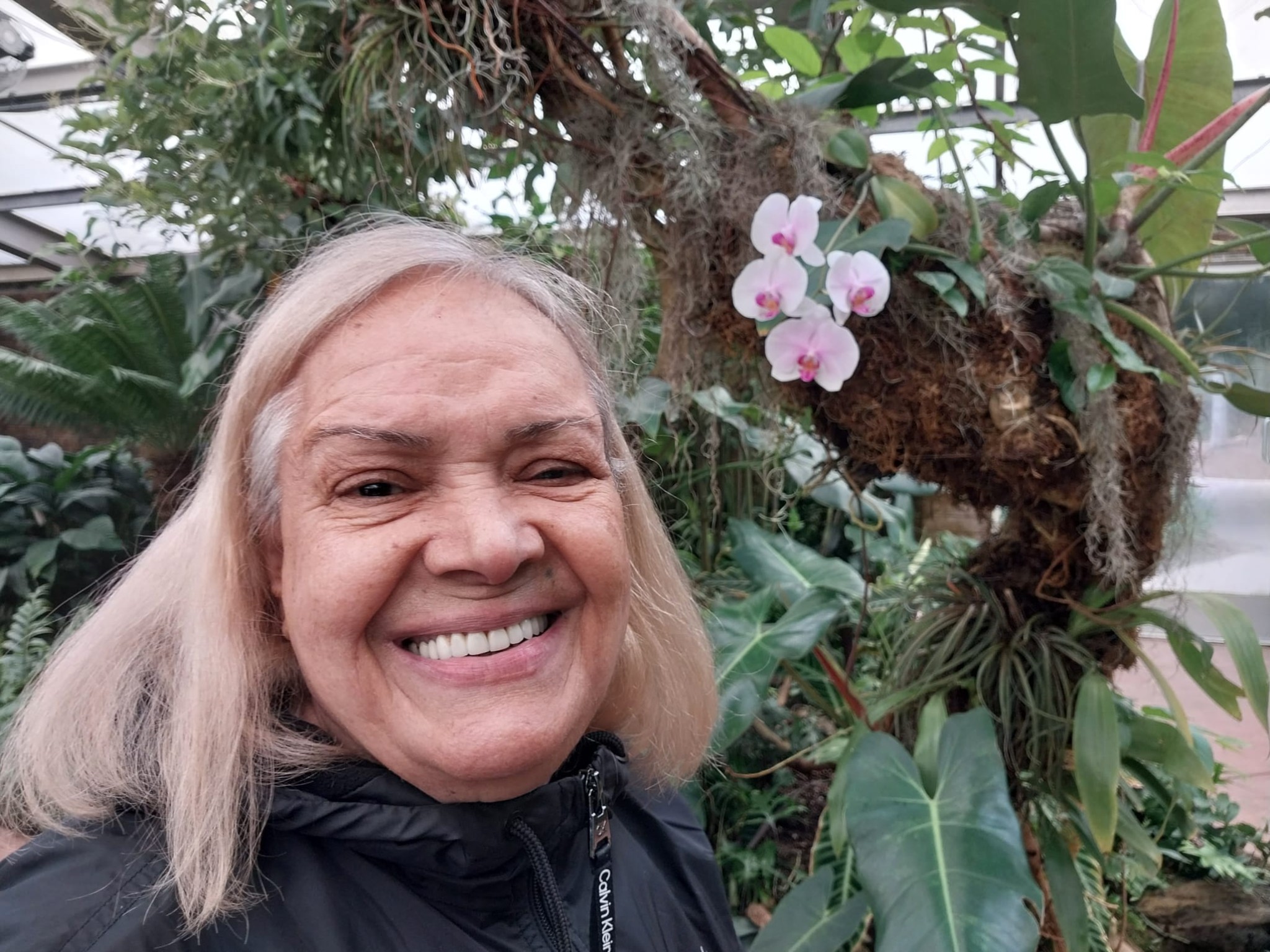 Maryam smiling beside orchids
